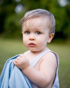 Toddler holding security blanket in park or garden