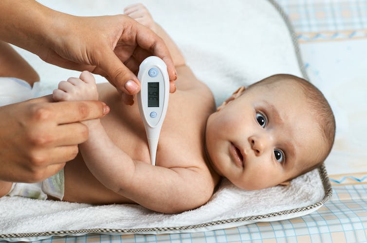 Baby with thermometer under its arm.