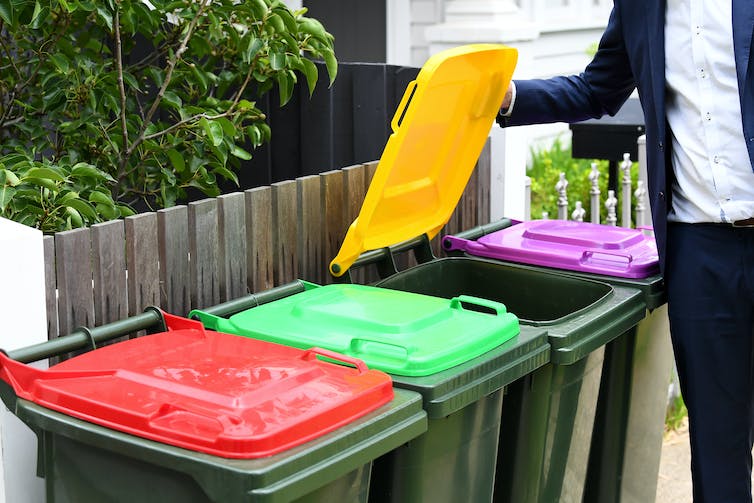 man opens lid to recycling bin